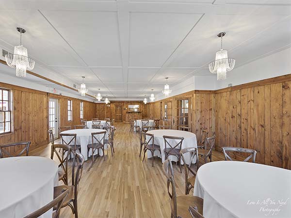 The Small Ballroom set with round tables and cross-back chairs under crystal chandeliers