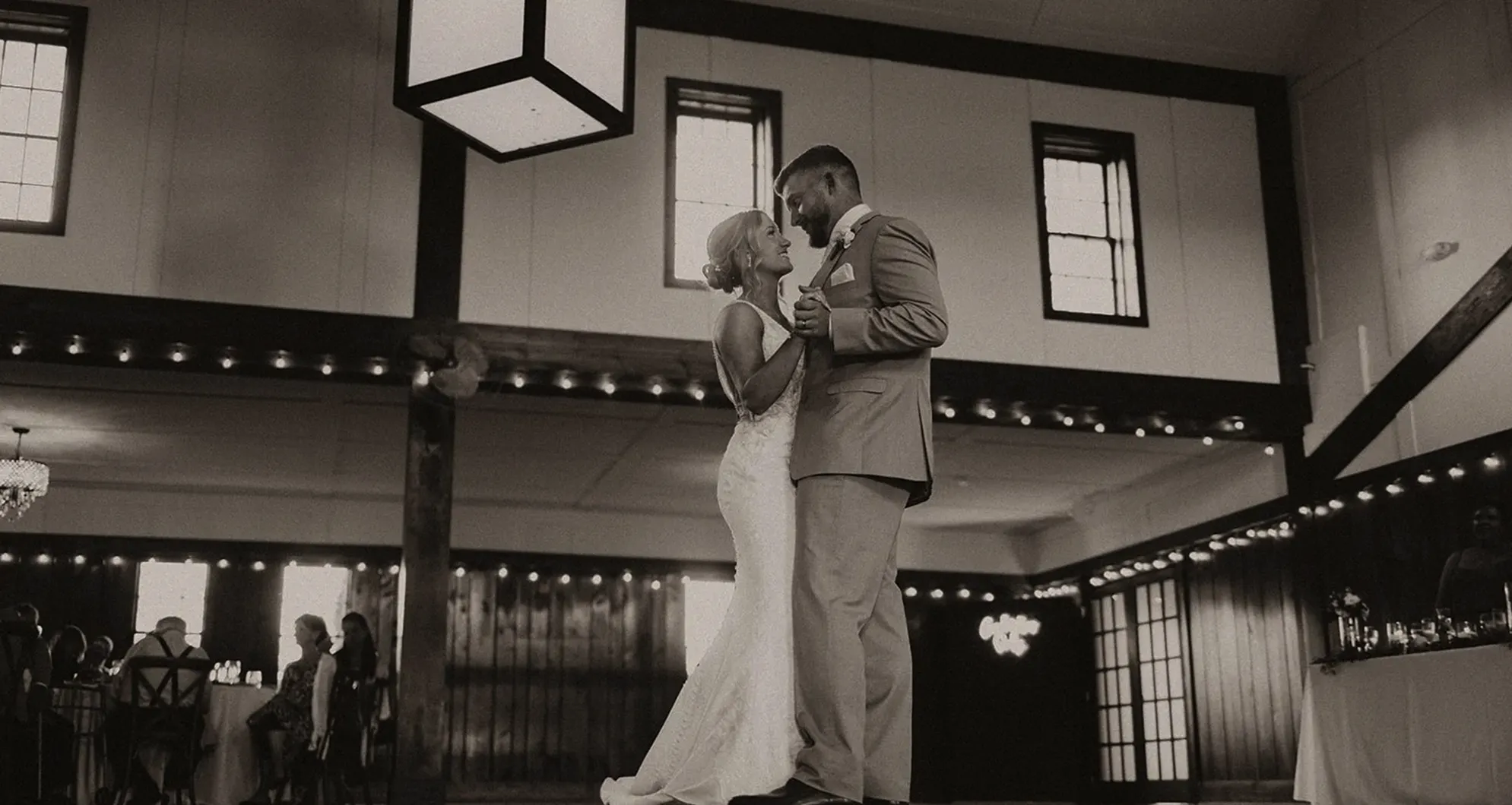 Bride and groom kiss beneath the tall evergreens outside Columbia Ballroom